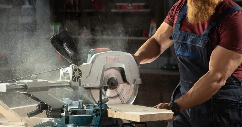 bearded man cuts board with type of miter saw