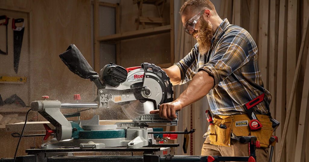 man cutting through a board using a miter saw