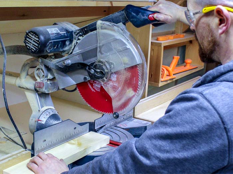 man using miter saw to cut board